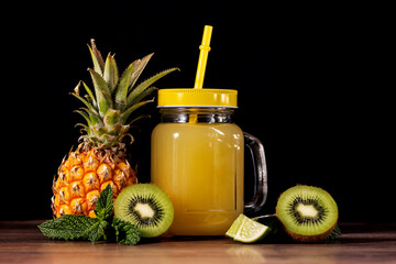 Natural juice mug on a wooden table.With kiwi and lime and pineapple.