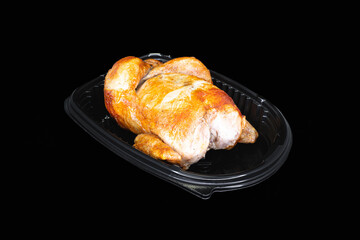 Roasted whole chicken in a black package on a black background