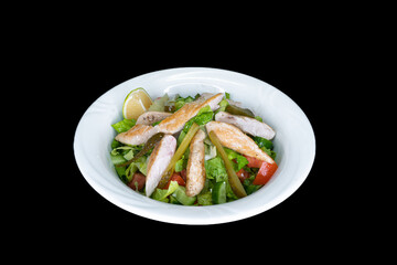 Chicken Caesar Salad in a white plate on a black background
