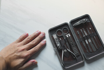 Holding hand cutting nails manicure and pedicure tool set concept, cosmetic accessories for nails, scissors, pusher cuticle and nail file, cleaning nails for protection dirt bacteria in nails.