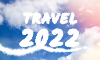 Naklejka na ściany i meble Travel in 2022. Inscription in clouds in bright glare of sunlight.