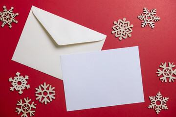 Christmas winter festive ornament. Blank paper card and envelope with wooden snowflake on red background. Minimal decoration. Invitation Christmas holiday party.