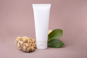 Blank cosmetic container with glossy green leafs and natural stone near it.Eco friendly concept.