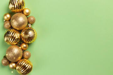 Christmas frame with golden glitter balls and decorations on green background with copy space