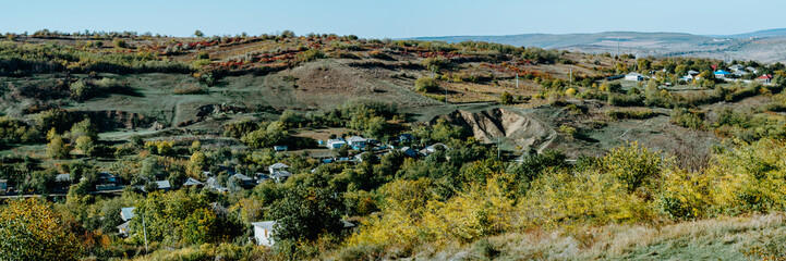 Autumn panorama of rural village nested between hills 