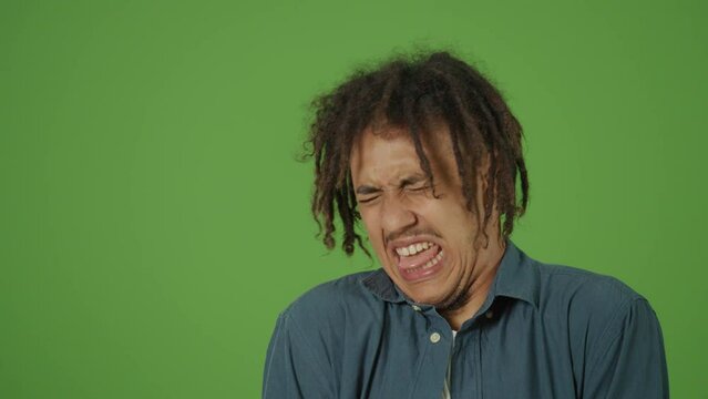Young Multicultural Curly Freelancer Student in Denim Shirt Emotionally Reacting with Disgust on Something Ugly,Abominable and Nasty Sticking out Tongue on Green Screen Background
