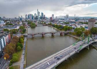 Fototapeta premium Dark and stormy day with a bridge crossing the river and a modern city skyline with skyscrapers in the distance