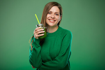 Young woman wering green sweater holding smoothie jar with drink. Isolated female advertising...