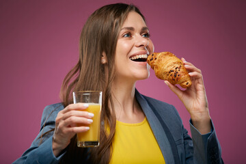 Smiling woman eating croissant with juice. Isolated advertising portrait on pink back. Girl looking up.