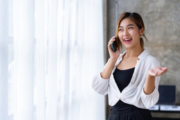 Beautiful and cute Asian business woman Office workers stand on the phone to talk and answer questions from customers in the office.