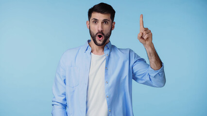 Fototapeta premium bearded man in shirt showing idea sign while looking at camera isolated on blue