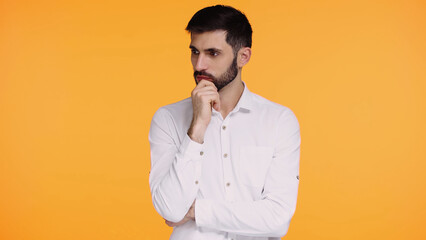 pensive man in white shirt touching beard while thinking isolated on yellow