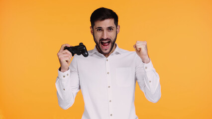 KYIV, UKRAINE - NOVEMBER 21, 2019: excited man in shirt holding joystick and rejoicing isolated on yellow