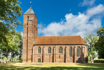 Summer landscape with historic landmark the Clemenskerk outside the village center of Havelte in the Dutch province of Drenthe surrounded with old oak trees and a lawn in the foreground