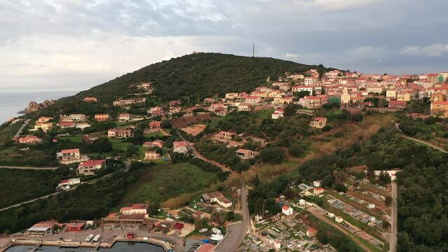 The port of Cargese at sunrise in Corsica on a partly cloudy day from a drone. Aerial view at water level of harbor town in Corsica in France