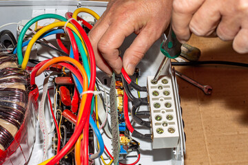 Voltage stabilizer repair. An electrician unscrews the power wires of the stabilizer