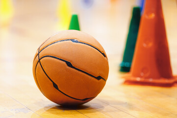 Basketball Training Game Background. Basketball on Wooden Court Floor Close Up with Blurred Training Cones. Basketball Practice Game Equipment