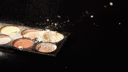 Close up view of face powder pouring on palette on black background