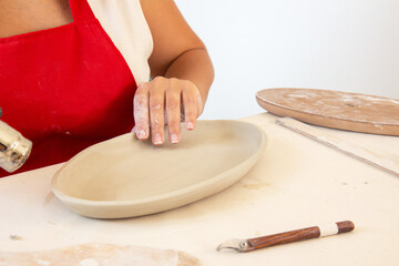 Woman potter in the process of work. Cropped image of an unrecognizable female pottery worker working with clay in a cozy workshop. With contains certain grain or noise and soft focus