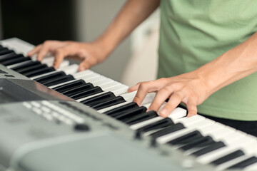 Teenager's hands on the keys of an electronic piano instrument, selective focus, the concept of...