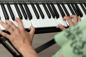 Teenager's hands on the keys of an electronic piano instrument, selective focus, the concept of...