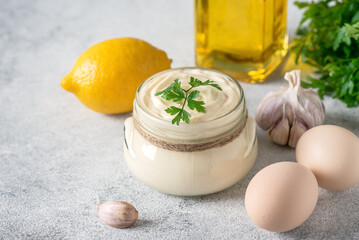 Aioli sauce with ingredients on a light gray grunge background. Side view, selective focus, copy...