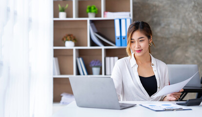 Fototapeta na wymiar Attractive and confident, successful Asian businesswoman sitting on her laptop in the office.