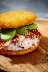 Pan-Asian cuisine concept. Japanese sushi burger made from rice bread, crab meat, avokado and wasabi sauce. Serving on wooden board. copy space