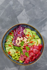 Top view on poke salad with tuna and green vegetable in the bowls on gray background. Copy space.