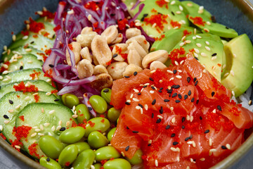 Top view on poke salad with tuna and green vegetable in the bowls on gray background. Copy space.