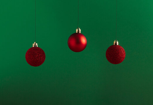 Creative Christmas concept made of red baubles on bold green background. Minimal New Year advertisement concept. Mock up showcase for product, promotion, sale or presentation.