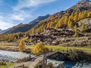 Blatten, Switzerland - October 19. 2022: Alps village with tradtional wooden chalets in autumn on the larch forest hillside in Loetschental valley, Canton Valais