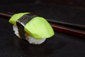 Sushi covered with avocado on wooden board gray stone background.