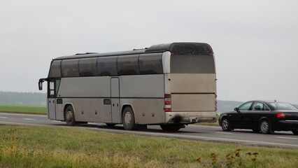 Old gray passenger bus overtake a car on highway closeup . Passenger transportation safety - obrazy, fototapety, plakaty