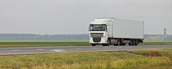 White semi truck van drive on countryside highway road on green field . Front side view . International transportation logistics