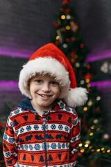 smiling cute and handsome boy in christmas pajamas, christmas background with christmas tree. High quality photo