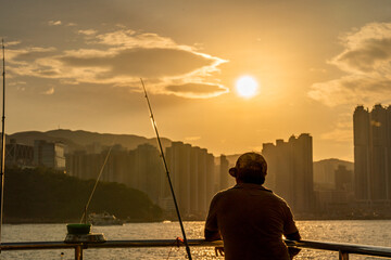 An elder fishing under sunset