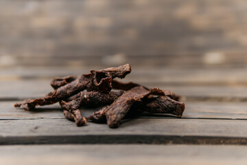 Chewy and delicious beef jerky, dried meat cut into slices on a wooden background, warm picture. High quality photo