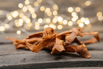 Chewy and delicious chiken jerky, dried meat cut into slices on a wooden background, warm picture with bokeh. High quality photo