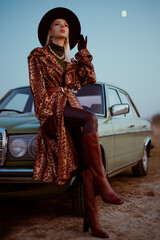 Elegant fashionable woman wearing trendy leopard print trench coat, belt, hat, chain necklace,...