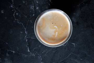 top view of a cup of coffee on a black background with space for text, directly above shot of coffee with milk in a glass on dark background - Powered by Adobe