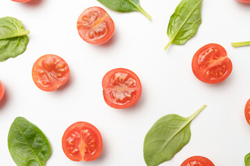 Beautiful border made of fresh cherry tomatoes with spinach leaves, Vegan diet food isolated on white, vegetable pattern, top view