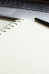 Blank notebook page for input text. Modern workspace on a white desk table with laptop, keyboard and other office supplies. Still life workplace view with copy space. Selective focus.