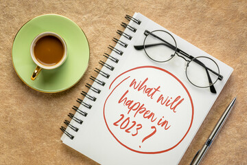 What will happen in 2023 ? Handwriting in a spiral notebook with a cup of coffee. Personal, business and financial trends and expectations in New Year.