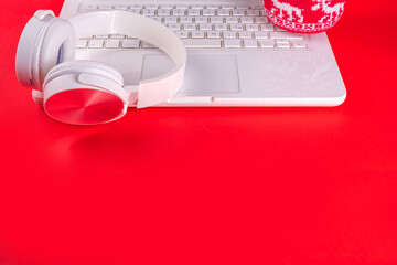 Festive red composition with white laptop computer, headphones, big cup for hot chocolate....