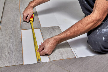 Laying laminate flooring.The repairman measures the distance for the laminated board with a tape measure