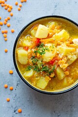 Soup with red lentils and vegetables in a bowl on a blue background.Traditional dish of Turkish or Arabic cuisine, vegan healthy food.