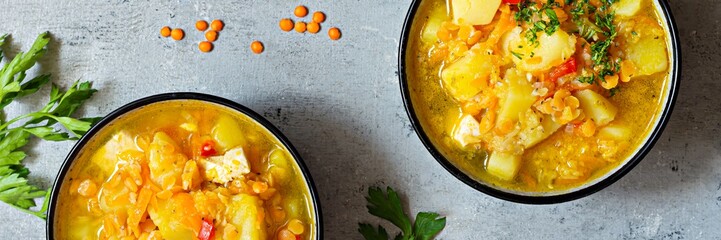 Soup with red lentils and vegetables in a bowl on a blue background.Traditional dish of Turkish or Arabic cuisine, vegan healthy food, banner.