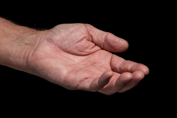 Closeup, wrinkled left hand of an elderly man asks for help on a black background.  