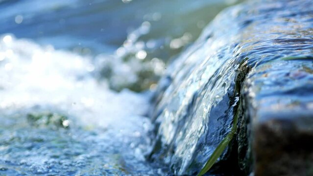 The rapid flow of the river near the dam, rapids, clear clear water close-up.